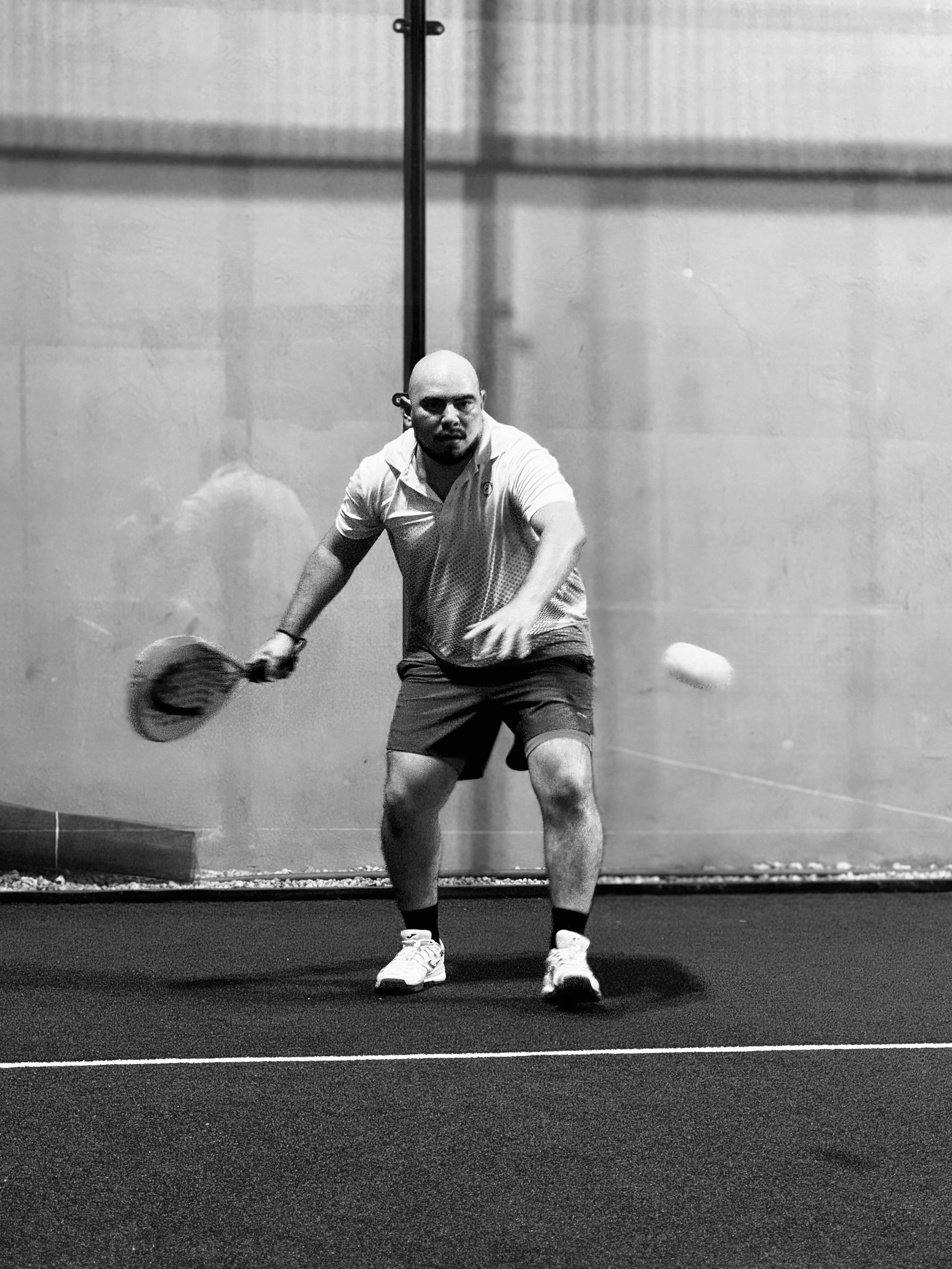 een geconcentreerd persoon die nadat de bal stuitert hem probeert te anticiperen zodat hij hem gecontroleerd terug kan slaan